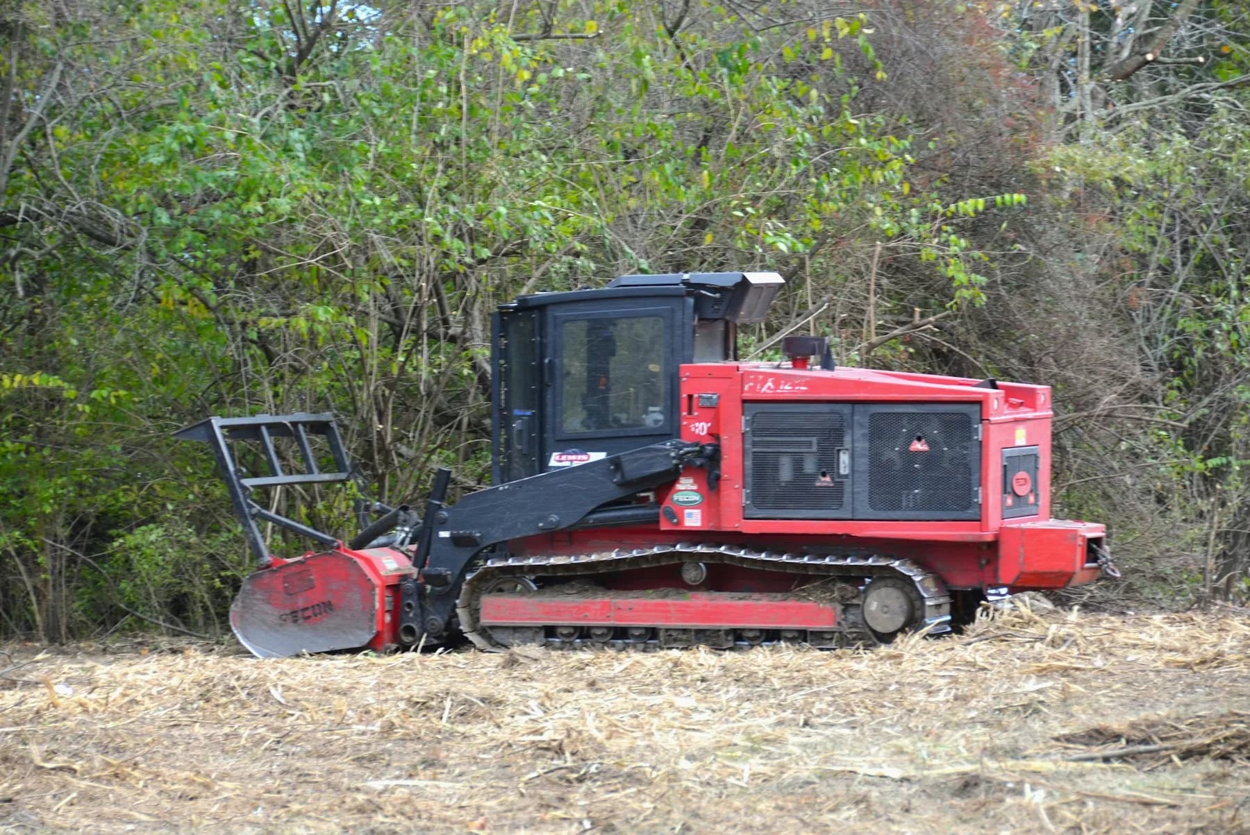 A tracked forestry mulcher beside dense woody vegetation