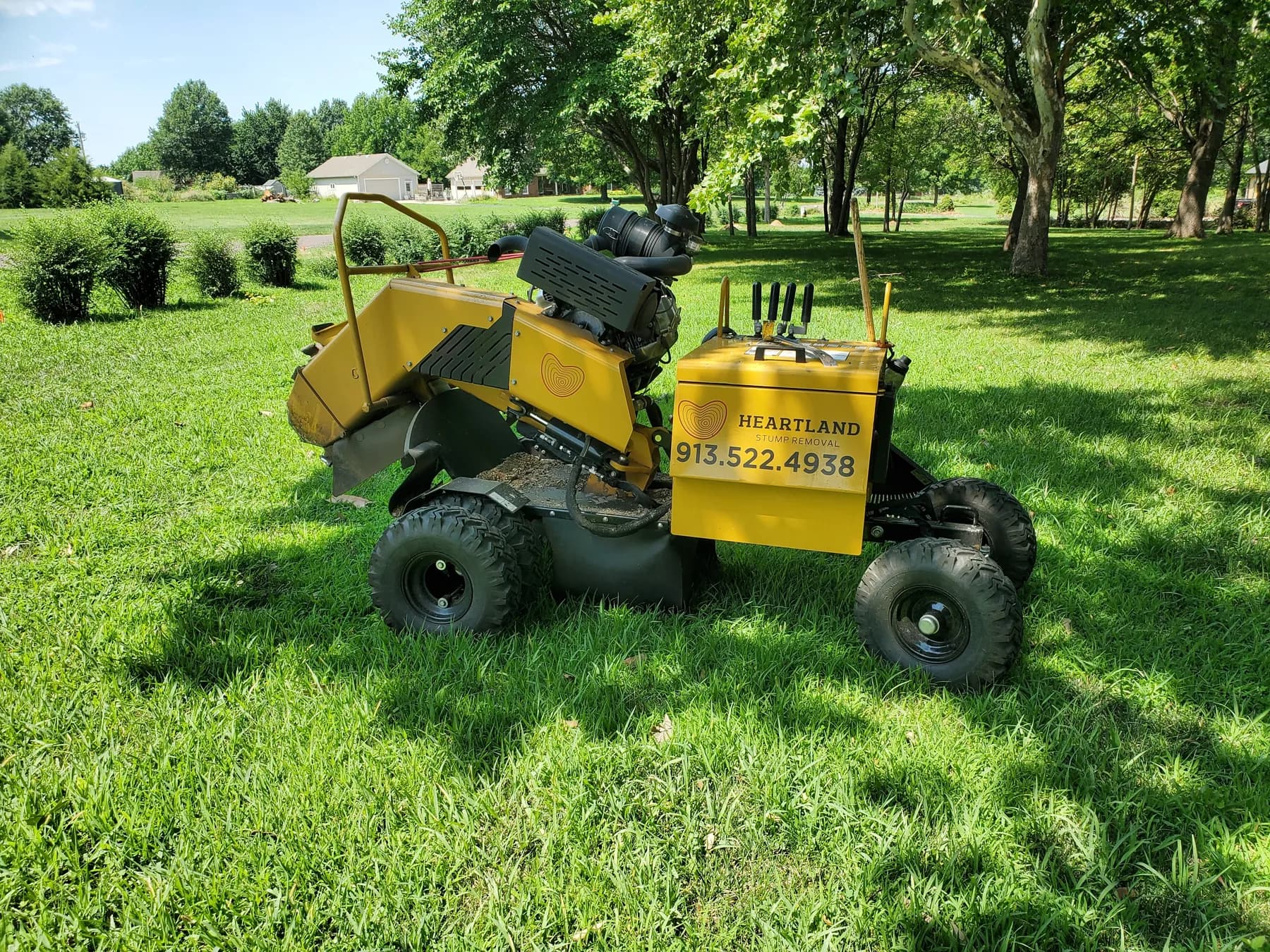Heartland's yellow stump grinder on a lawn, with its cutting wheel and branded controls visible