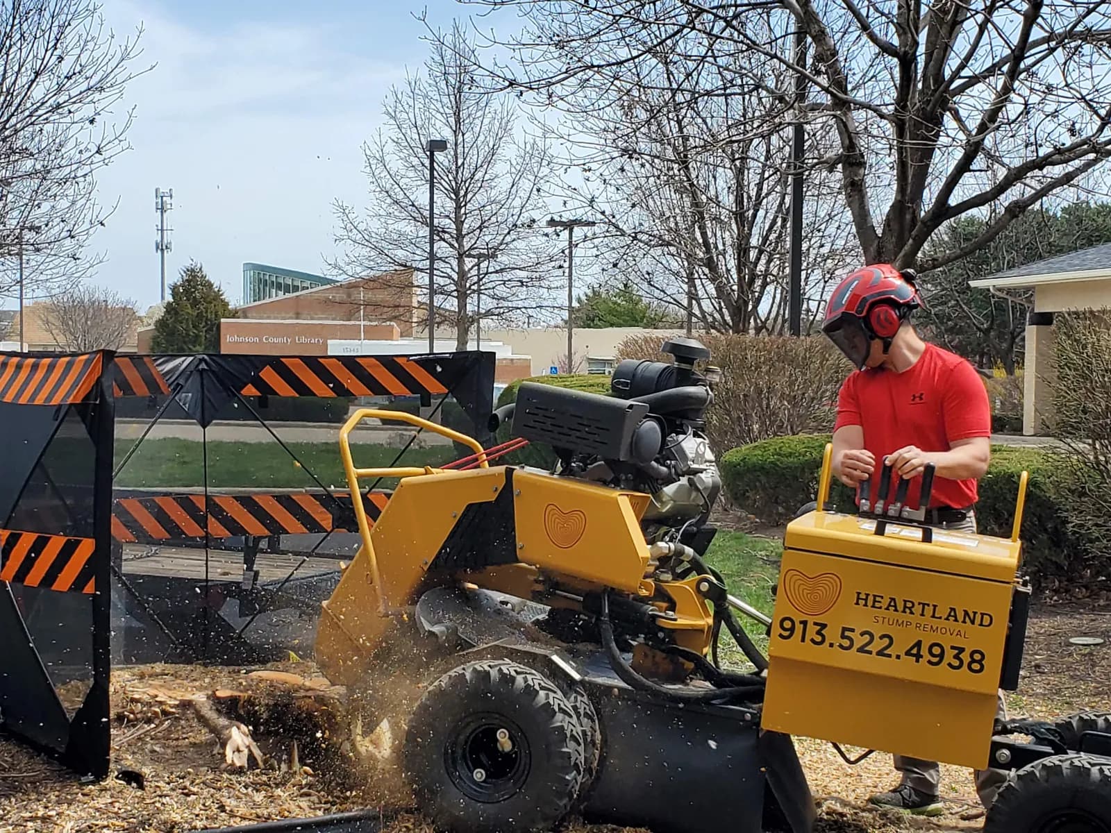 Matt operating Heartland’s stump grinder with protective screens around the work area