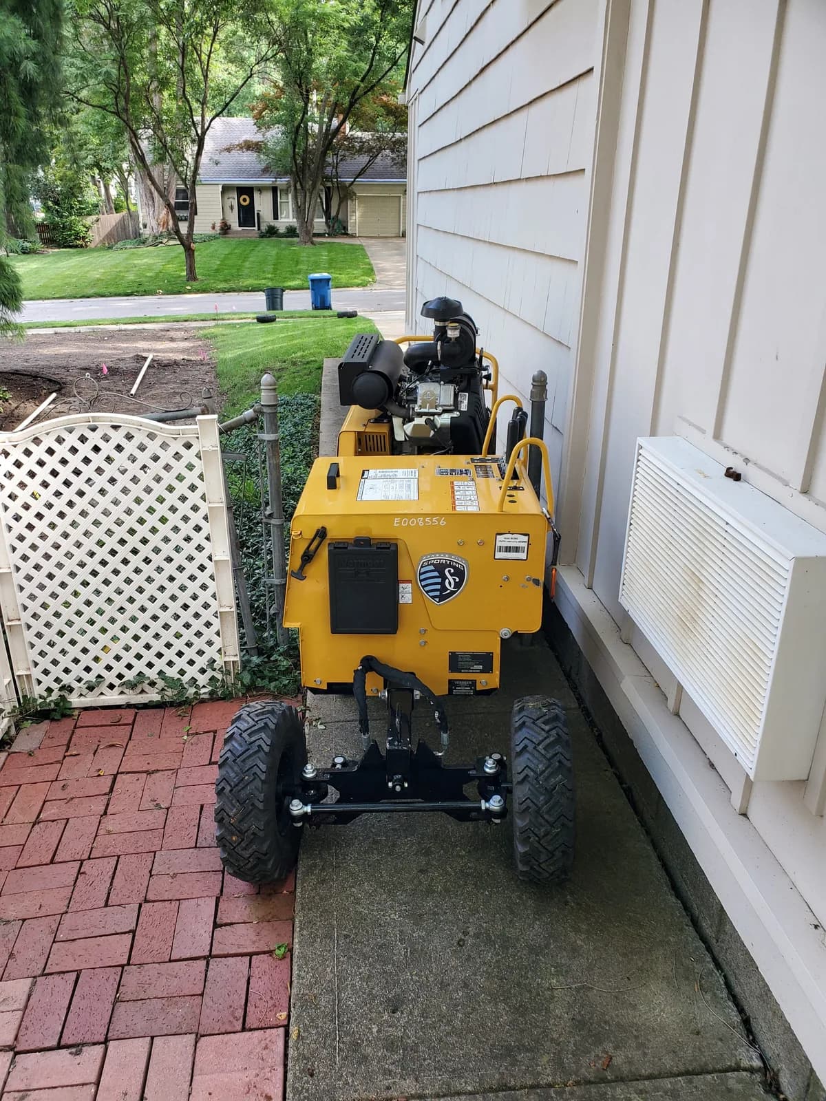 Heartland’s compact stump grinder passing through a narrow gate beside a house