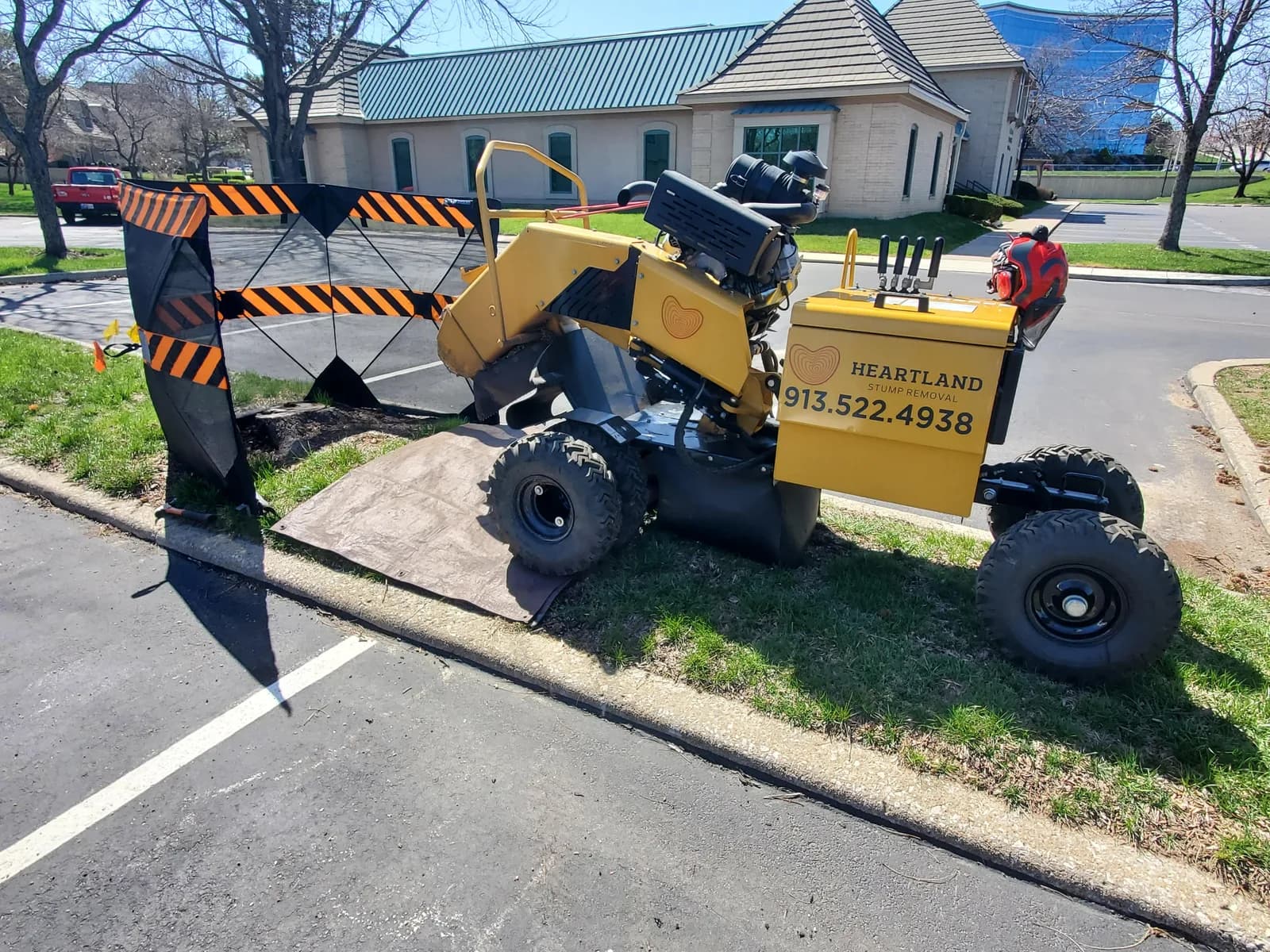 Heartland’s grinder and protective screens set beside a curb and paved parking area